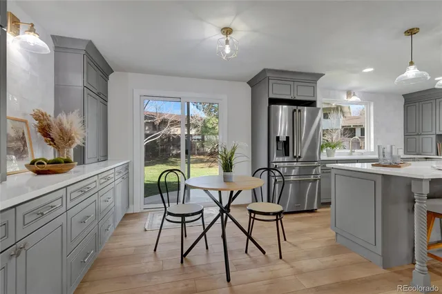 a dining hall with stainless steel appliances granite countertop a kitchen island a table and chairs in it