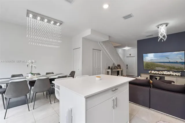a view of kitchen island a sink wooden floor and chairs