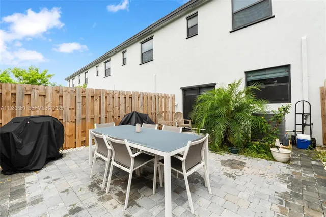 a patio with a table and chairs and potted plants