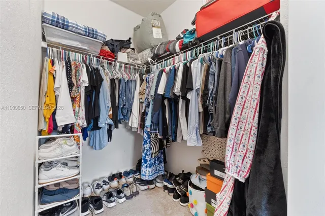 a view of walk in closet with clothes and shoes