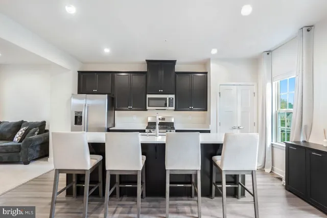 a kitchen with stainless steel appliances kitchen island granite countertop a table and chairs in it