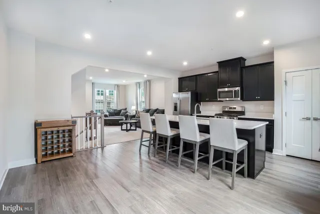 a living room with stainless steel appliances kitchen island granite countertop wooden floor a dining table and chairs