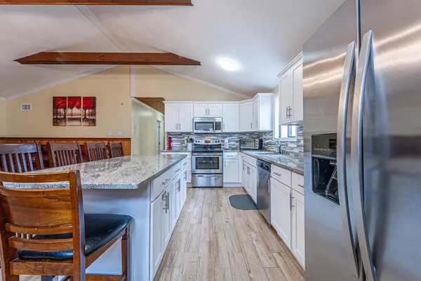 a kitchen with stainless steel appliances granite countertop a refrigerator a stove and a sink