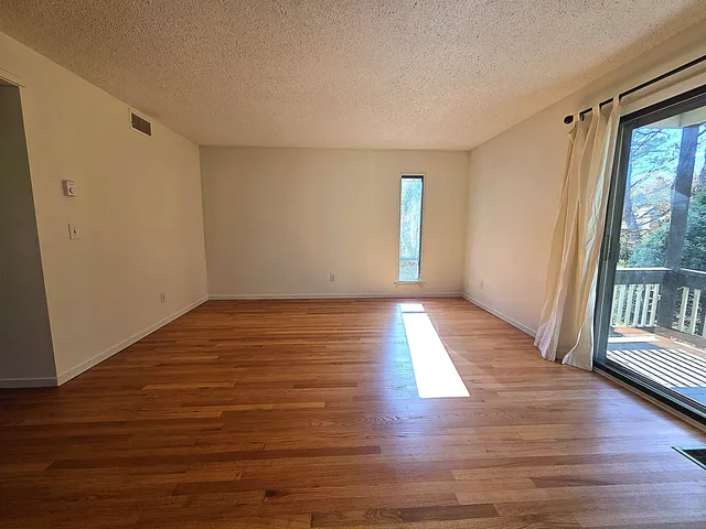a view of an empty room with wooden floor and a window