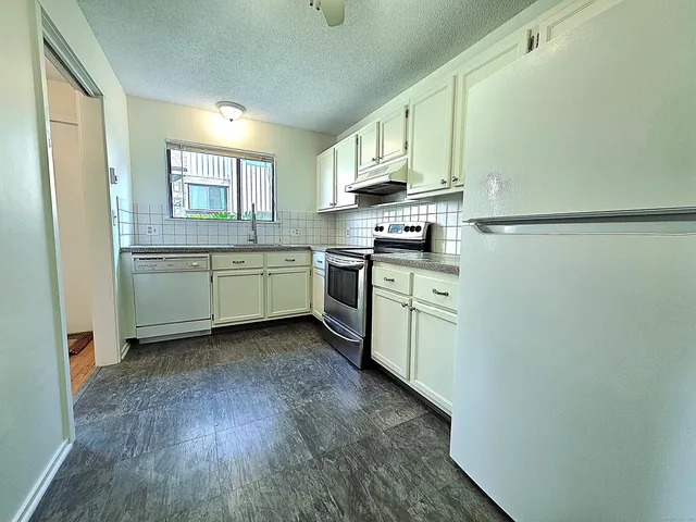 a kitchen with a sink cabinets stainless steel appliances and a window