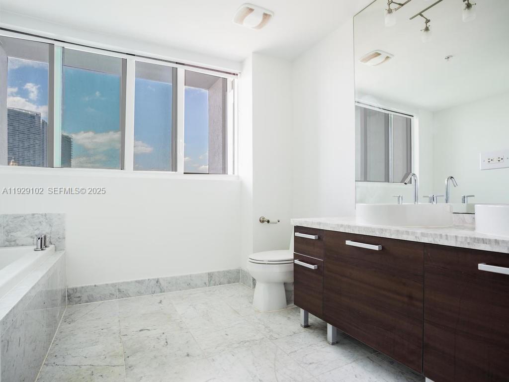 244 Biscayne Boulevard, Unit 2402 Miami, FL 33132 - Photo 18 of 19 a room with a sink vanity and mirror