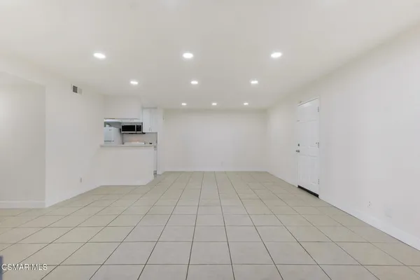an empty room with white kitchen appliances and cabinets