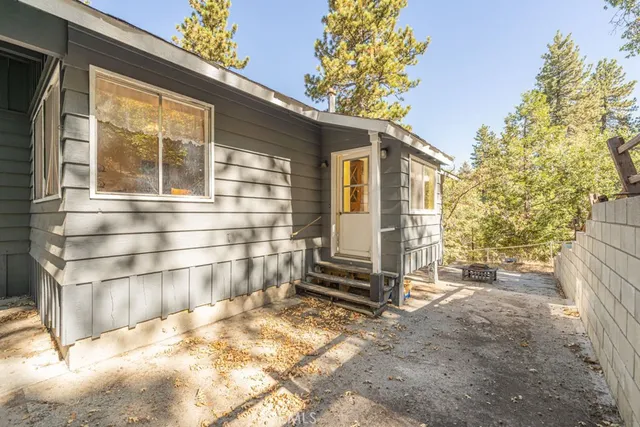 a view of a house with wooden fence and large trees