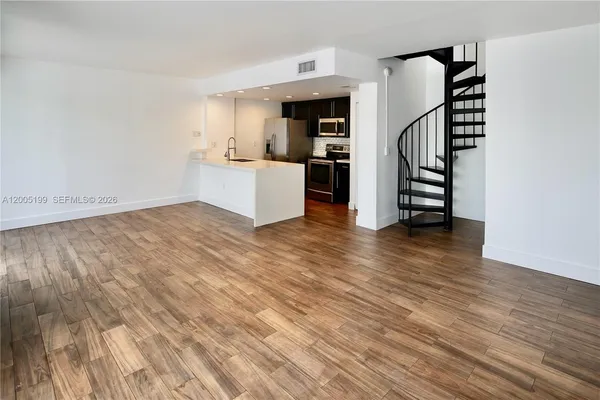 a view of a kitchen with wooden floor and electronic appliances