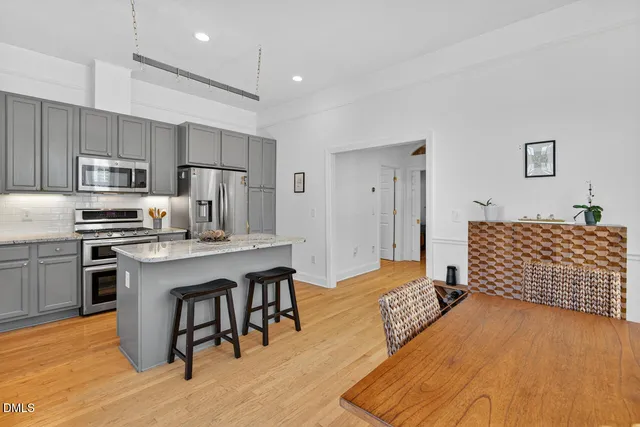 a kitchen with kitchen island granite countertop a refrigerator oven a sink a dining table and chairs