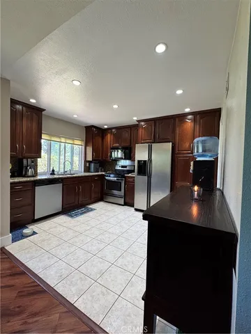 a large kitchen with stainless steel appliances kitchen island granite countertop a refrigerator a oven a sink counter space and wooden floor