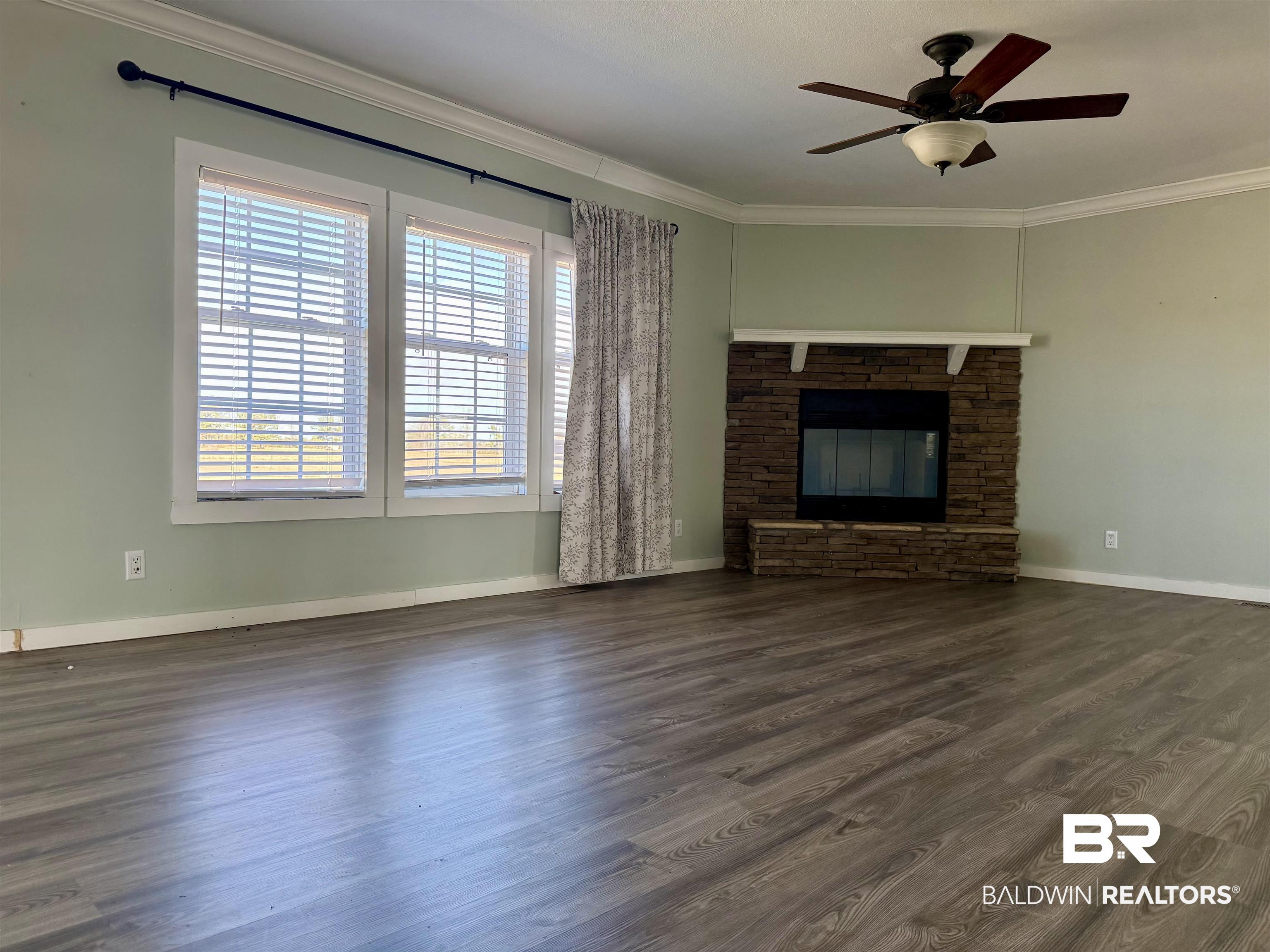 1064 Old Fannie Road Flomaton, AL 36441 - Photo 6 of 17 Unfurnished living room featuring dark wood-style flooring, ceiling fan, a fireplace, and ornamental molding