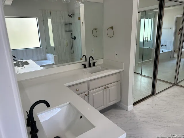 a bathroom with a double vanity sink mirror and shower