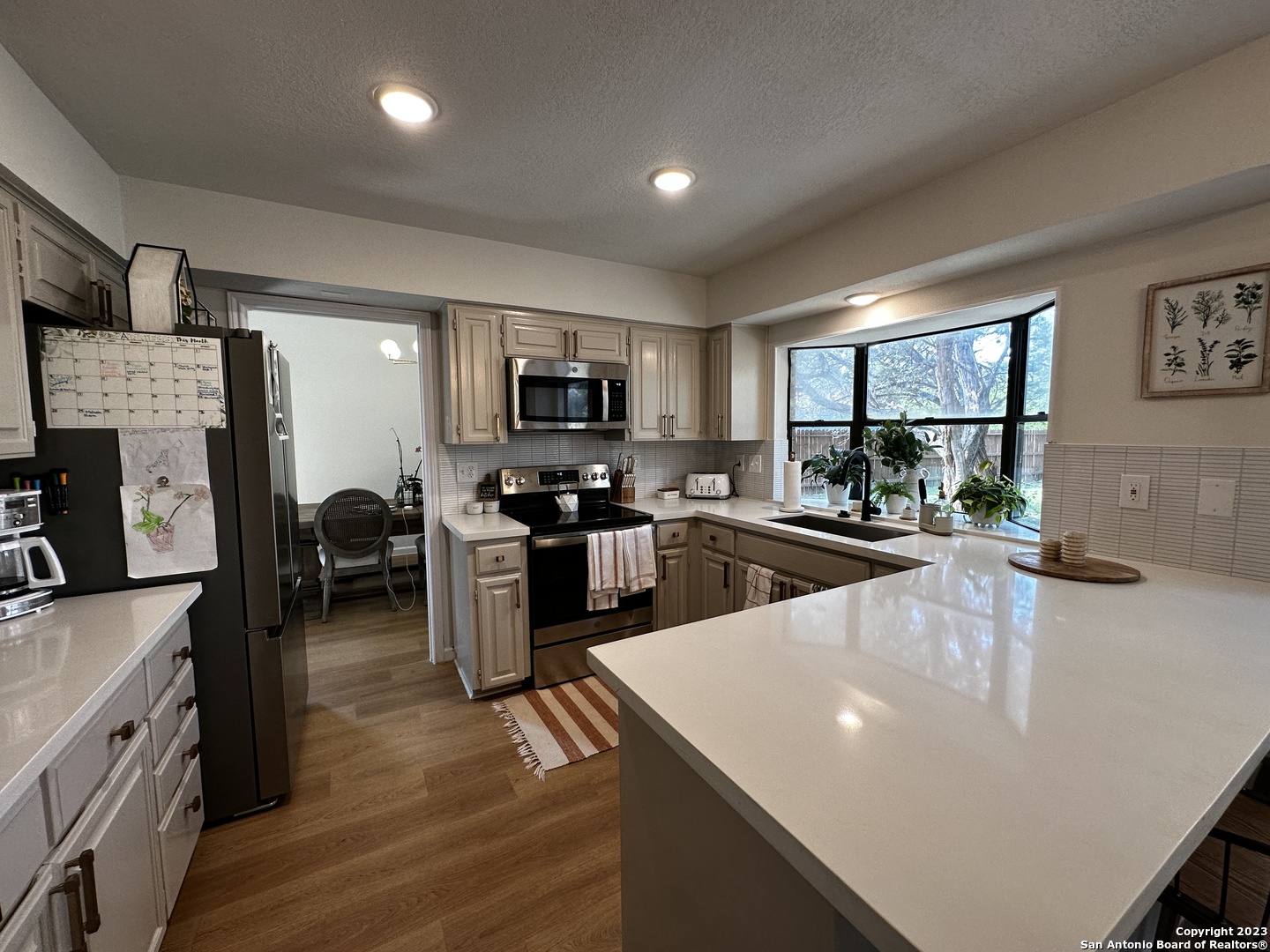 1722 Encino Spring San Antonio, TX 78259 - Photo 34 of 55 a kitchen with stainless steel appliances a stove a sink a refrigerator white cabinets and wooden floor