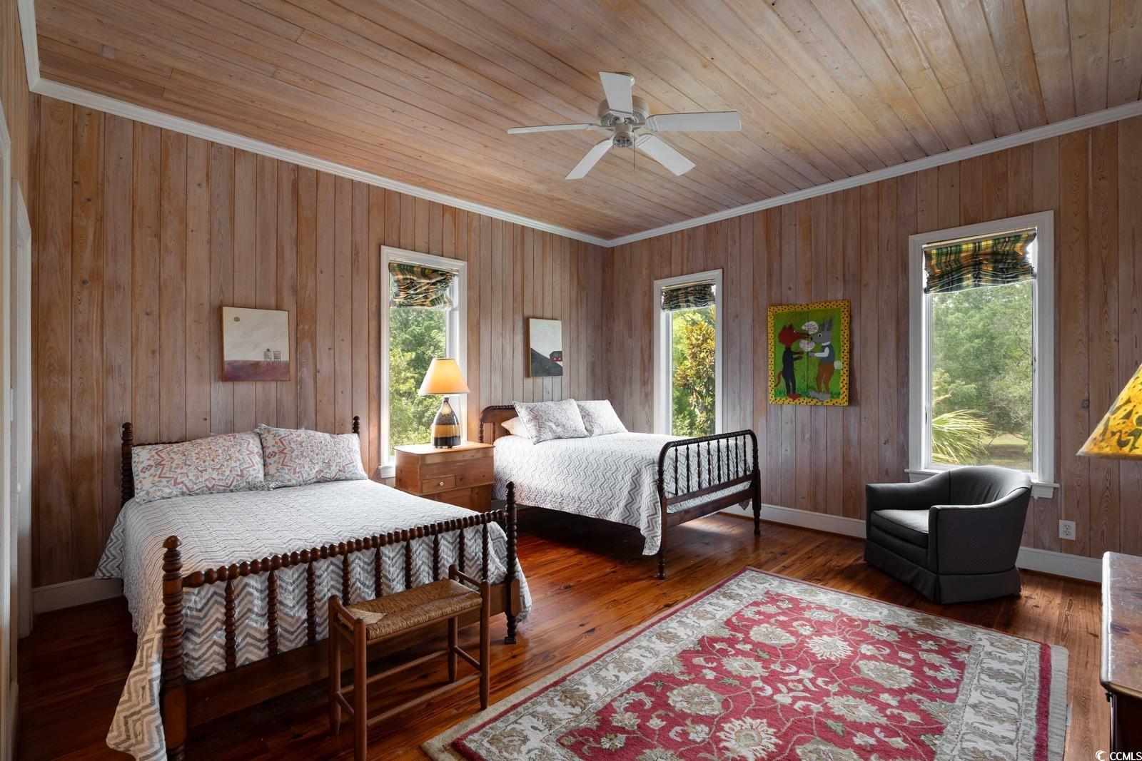 315 Lofton Court McClellanville, SC 29458 - Photo 35 of 40 Bedroom with crown molding, multiple windows, wooden walls, wooden ceiling, and a ceiling fan