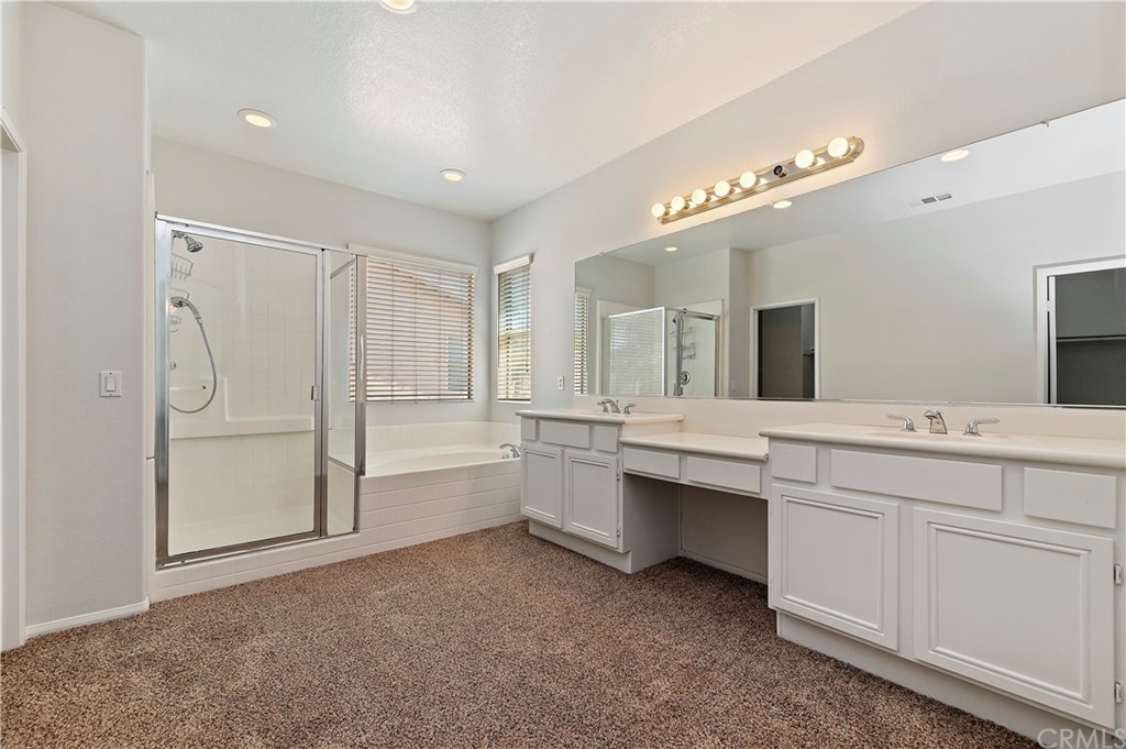 13527 Jasper Loop Eastvale, CA 92880 - Photo 25 of 37 a bathroom with a tub a double vanity sink and mirror