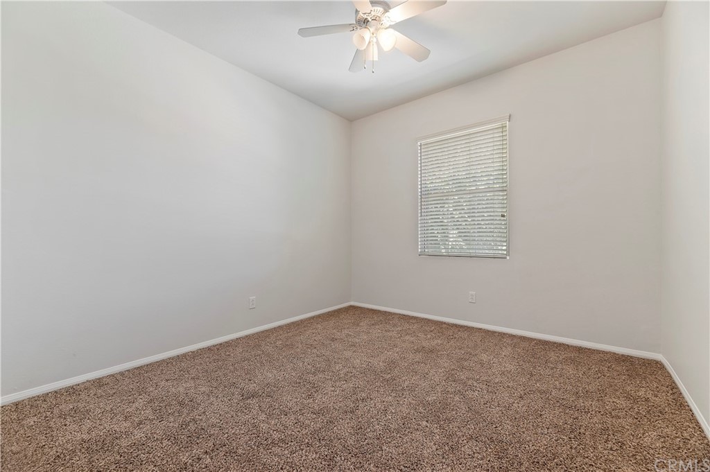 13527 Jasper Loop Eastvale, CA 92880 - Photo 29 of 37 an empty room with chandelier fan and windows