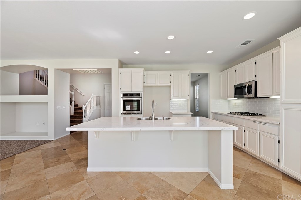 13527 Jasper Loop Eastvale, CA 92880 - Photo 10 of 37 a large white kitchen with stainless steel appliances