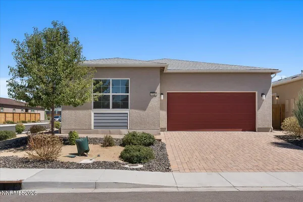 a front view of a house with garage and plants
