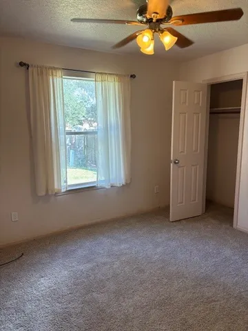 an empty room with windows and fan