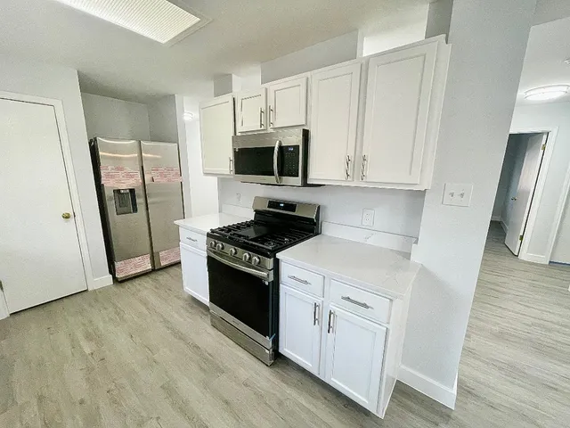 a kitchen with white cabinets and stainless steel appliances