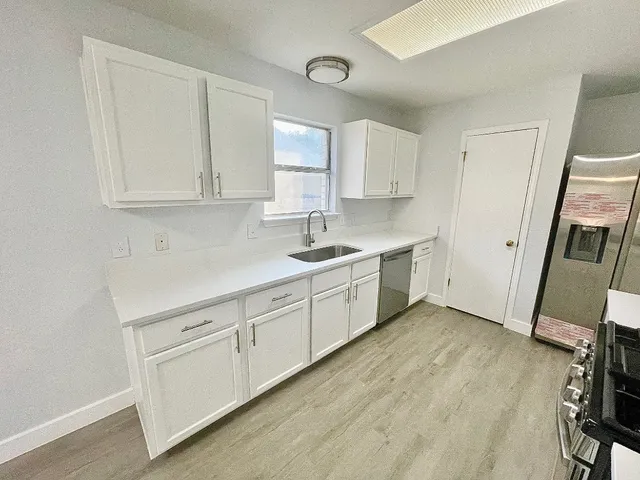a kitchen with white cabinets and sink
