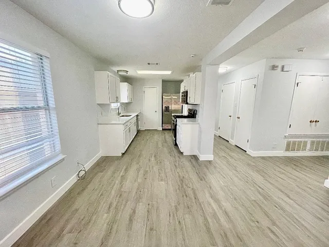 a view of a kitchen with a white cabinets and wooden floor
