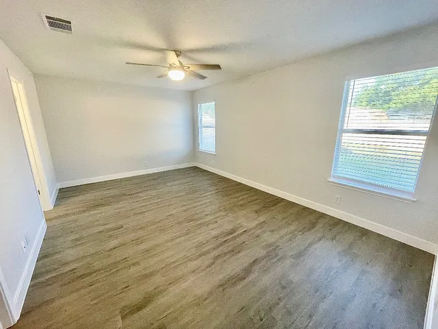 a view of an empty room with wooden floor and a window