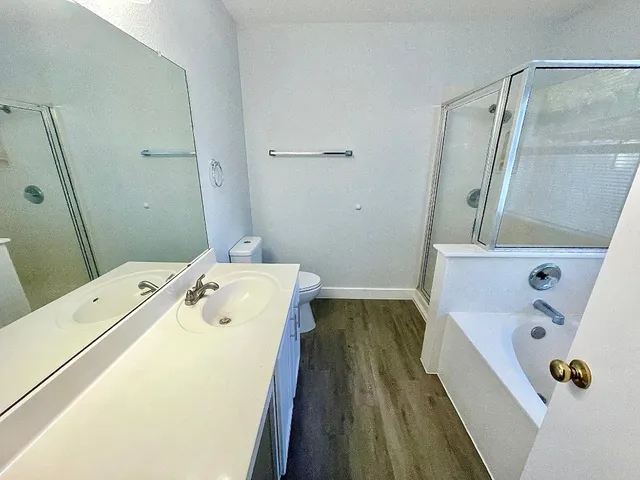 a bathroom with a tub sink and wooden floor