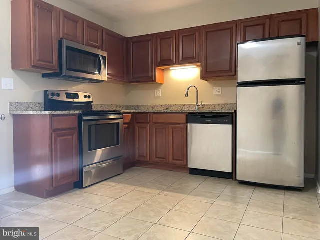 a kitchen with granite countertop a refrigerator and a stove top oven