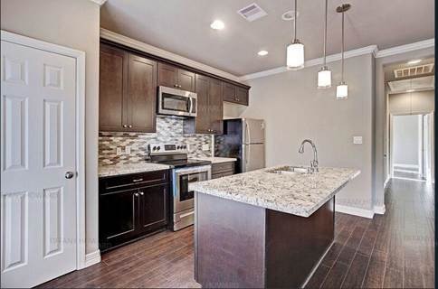 4204 Stassen Street, Unit B Houston, TX 77051 - Photo 7 of 11 a kitchen with kitchen island granite countertop wooden cabinets and refrigerator