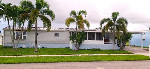 a front view of a house with a garden and palm trees