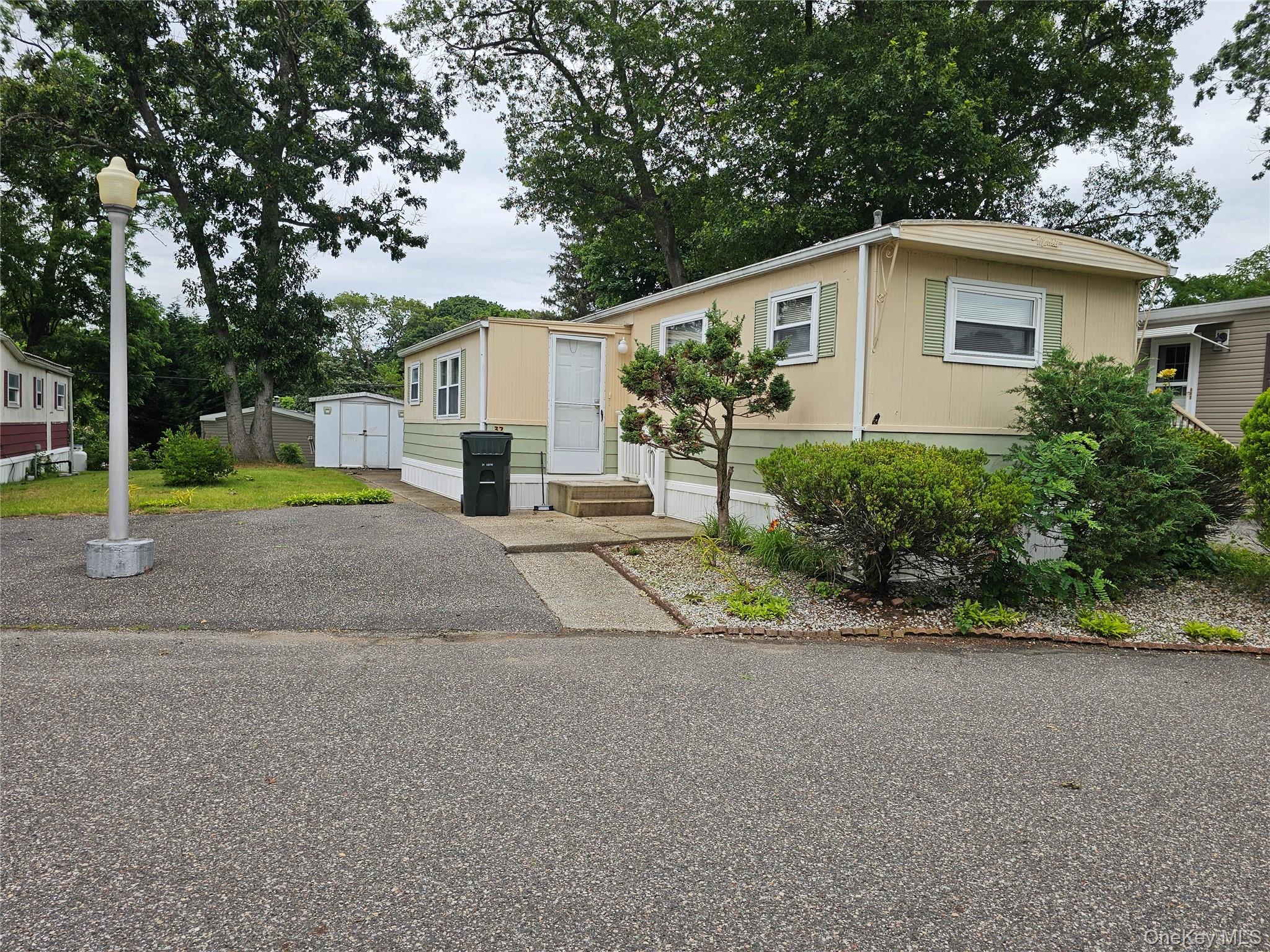 1964 River Road, Unit 37 Calverton, NY 11933 - Photo 1 of 13 a view of a house with a yard and large trees