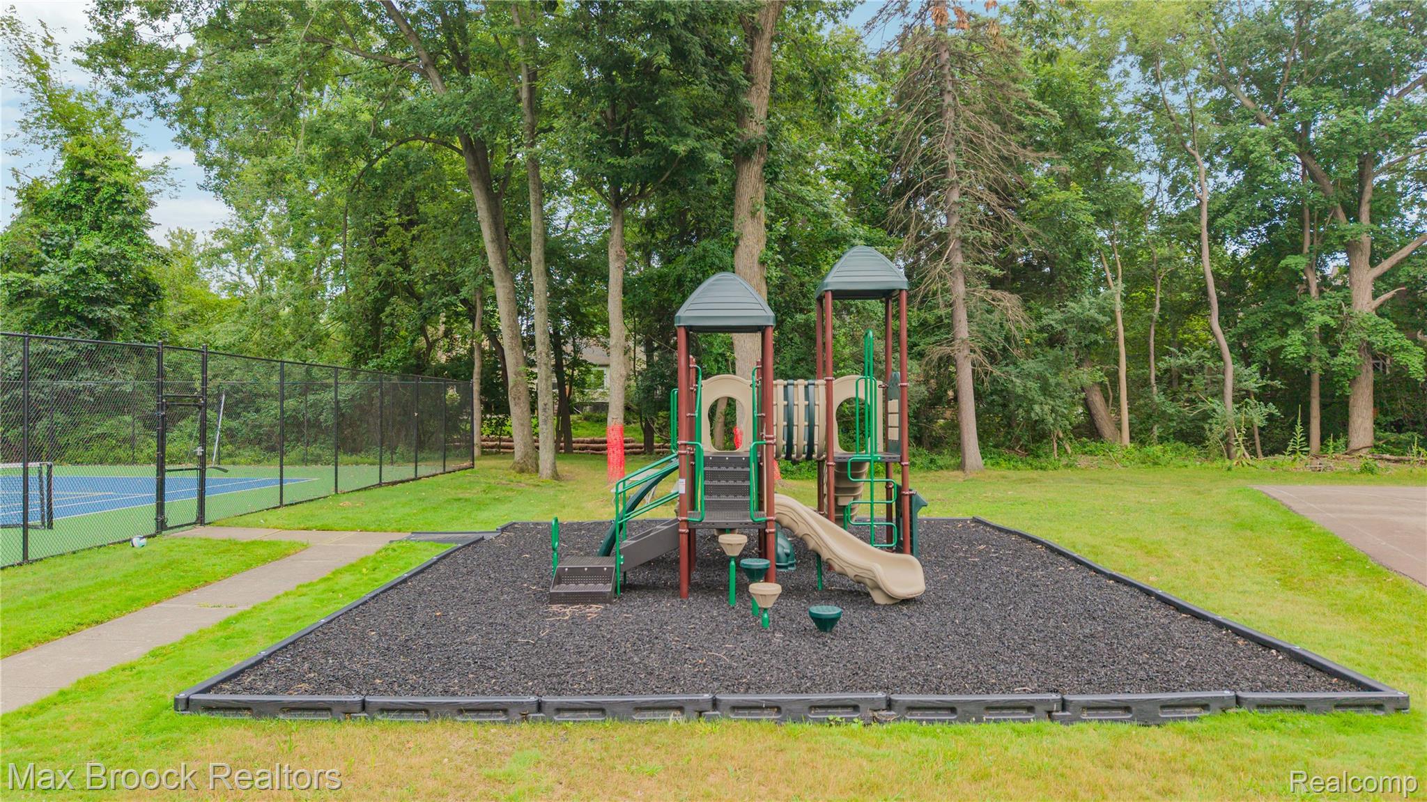 1157 Pine Ridge Court Rochester, MI 48306 - Photo 41 of 55 Expansive recreational grounds featuring a multi-level playground structure with slide and climbing components, situated on a rubberized safety surface