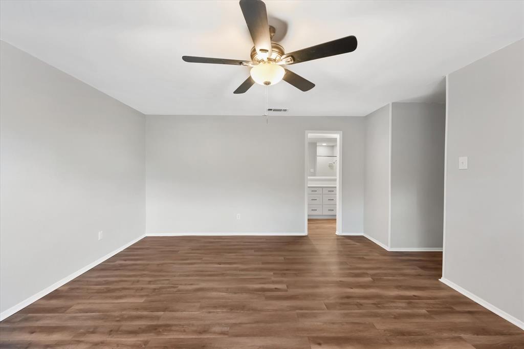 4005 Ridgebrook Drive Arlington, TX 76015 - Photo 13 of 18 Spacious primary bedroom featuring wood-finish flooring, light grey painted walls, white baseboards, and a ceiling fan with integrated lighting