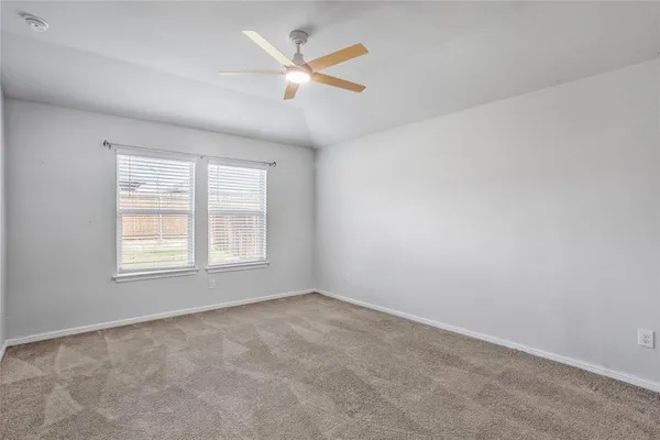 an empty room with ceiling fan and window