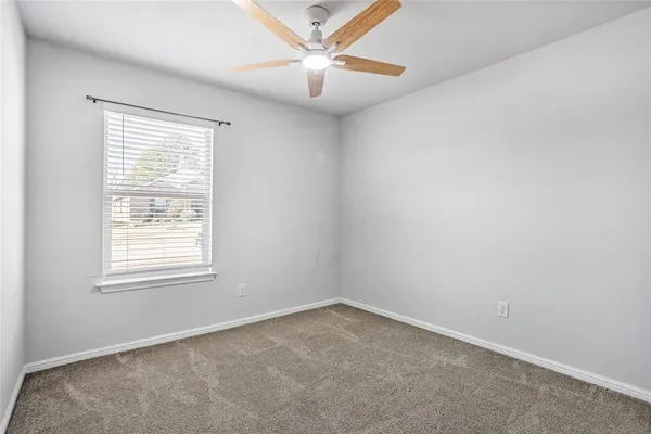 an empty room with a window and a fan