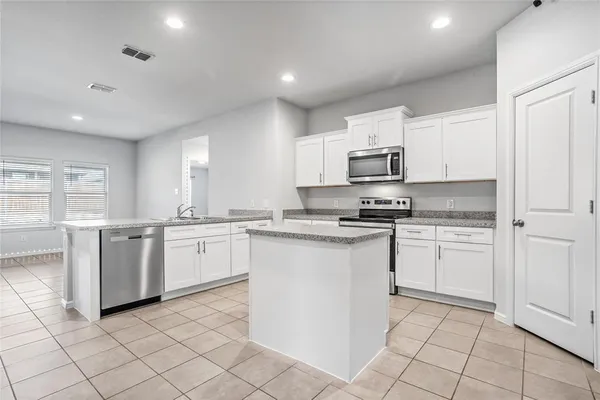 a kitchen with granite countertop white cabinets and stainless steel appliances