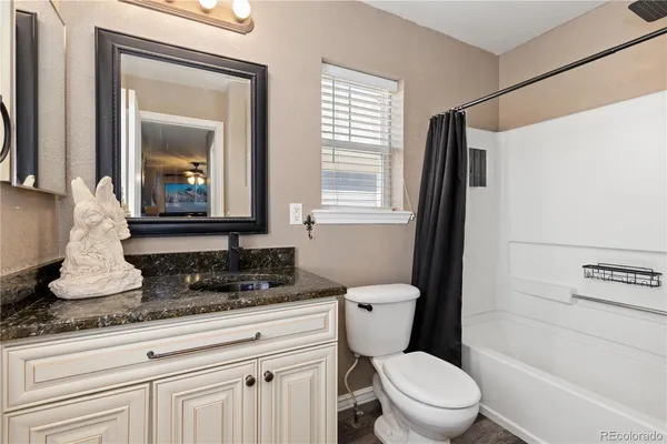 a bathroom with a granite countertop sink a toilet and mirror