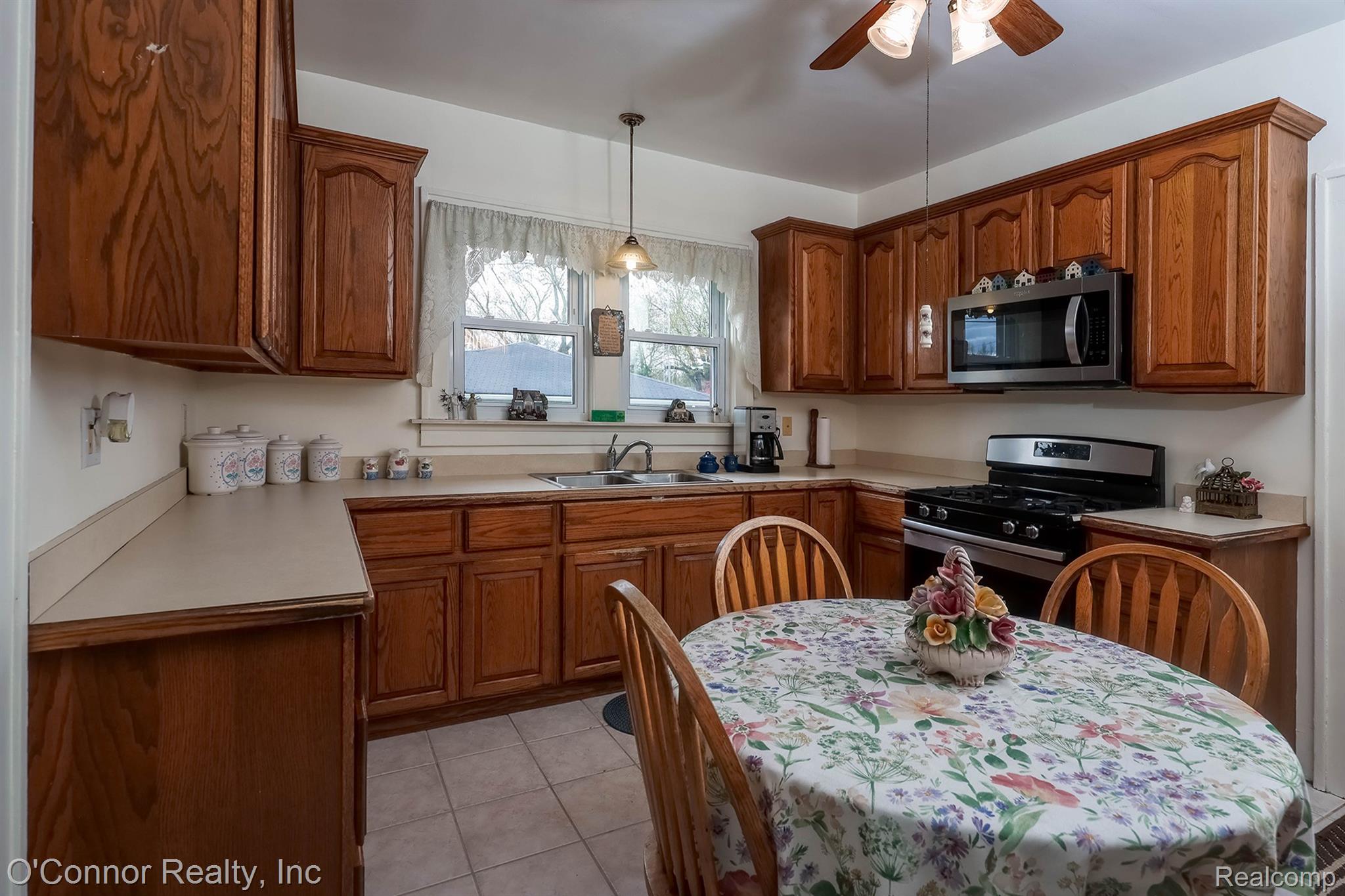 3323 Kinney Road Emmett, MI 48022 - Photo 13 of 29 Kitchen featuring wood cabinetry, stainless steel microwave, gas range, and a ceiling fan with integrated lighting
