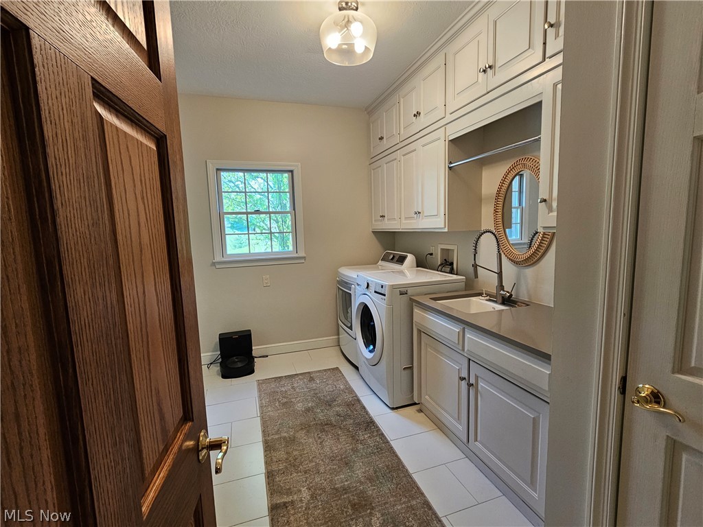 2363 Tabor Ridge Road Northeast New Philadelphia, OH 44663 - Photo 21 of 42 Laundry space featuring white cabinetry, a utility sink with a gooseneck faucet, light-toned countertops, and tile flooring