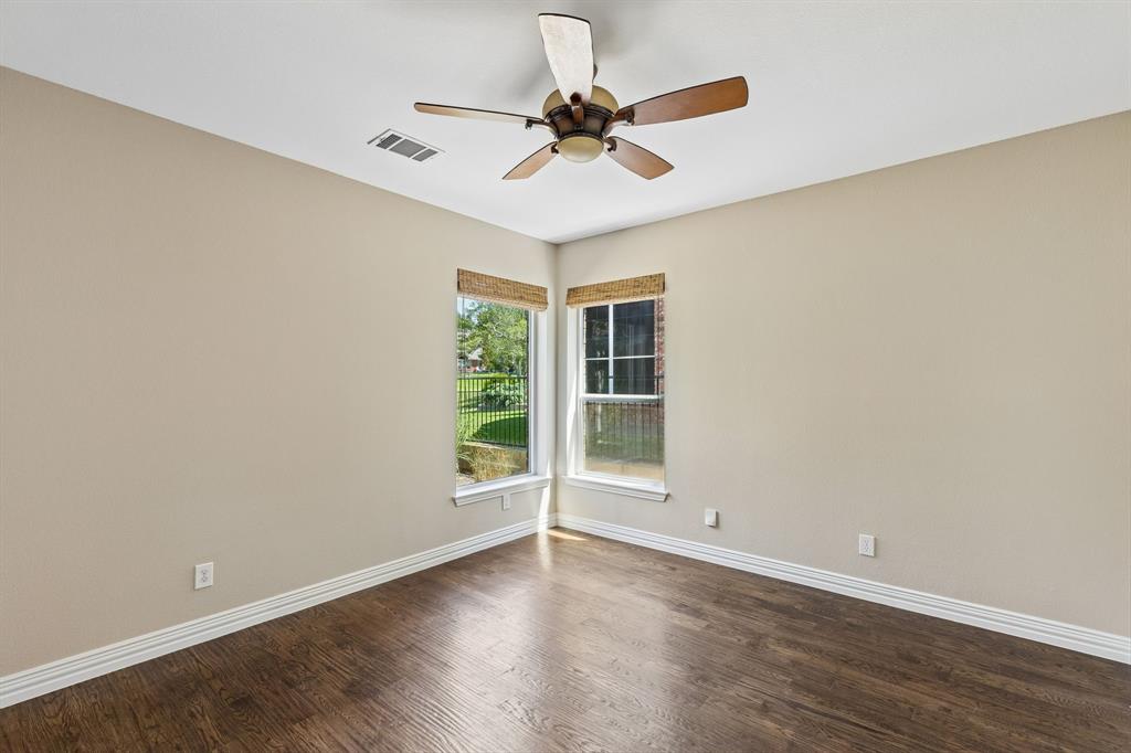 2925 Sunset Ridge McKinney, TX 75072 - Photo 7 of 33 Private first-floor guest bedroom featuring rich hardwood flooring, peaceful golf course views, and flexible use as a guest suite, home office, or flex space.