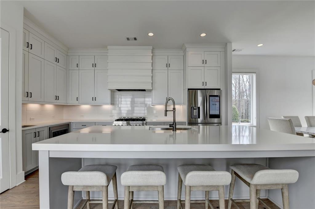 6785 Halcyon Way Alpharetta, GA 30005 - Photo 27 of 90 a kitchen with stainless steel appliances granite countertop a table chairs in it and wooden floors