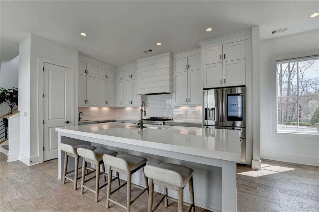 6785 Halcyon Way Alpharetta, GA 30005 - Photo 28 of 90 a kitchen with stainless steel appliances granite countertop a table chairs refrigerator and sink