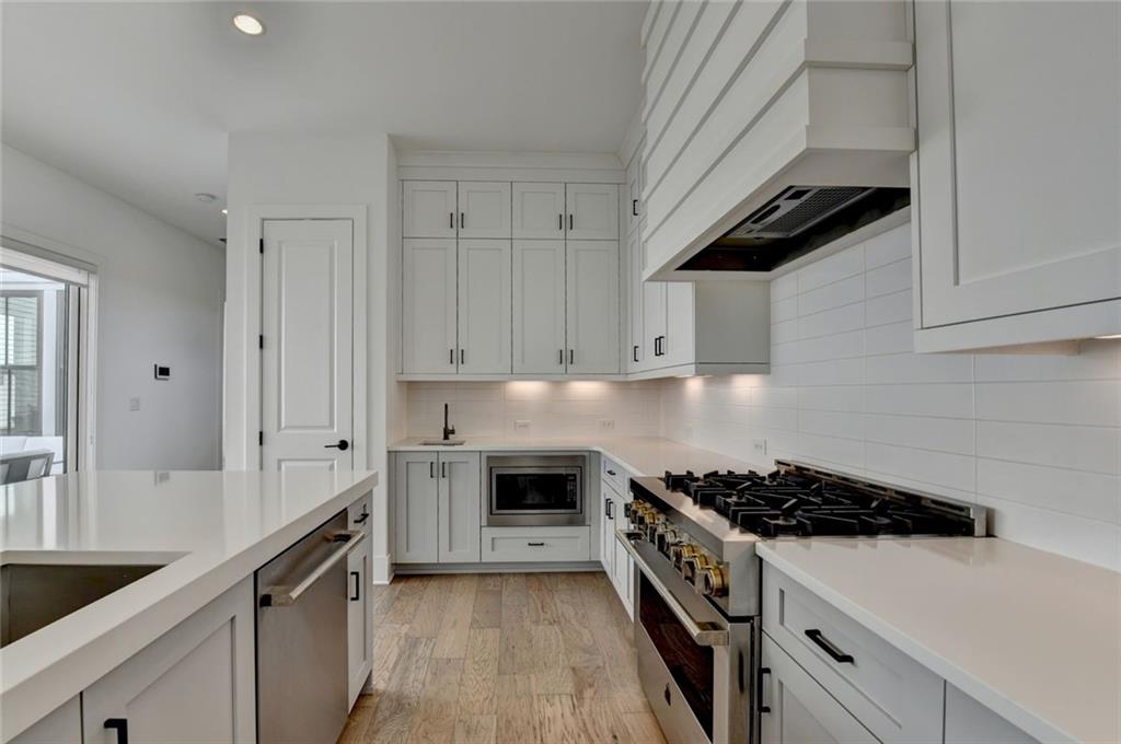 6785 Halcyon Way Alpharetta, GA 30005 - Photo 33 of 90 a kitchen with stainless steel appliances a stove a sink and white cabinets