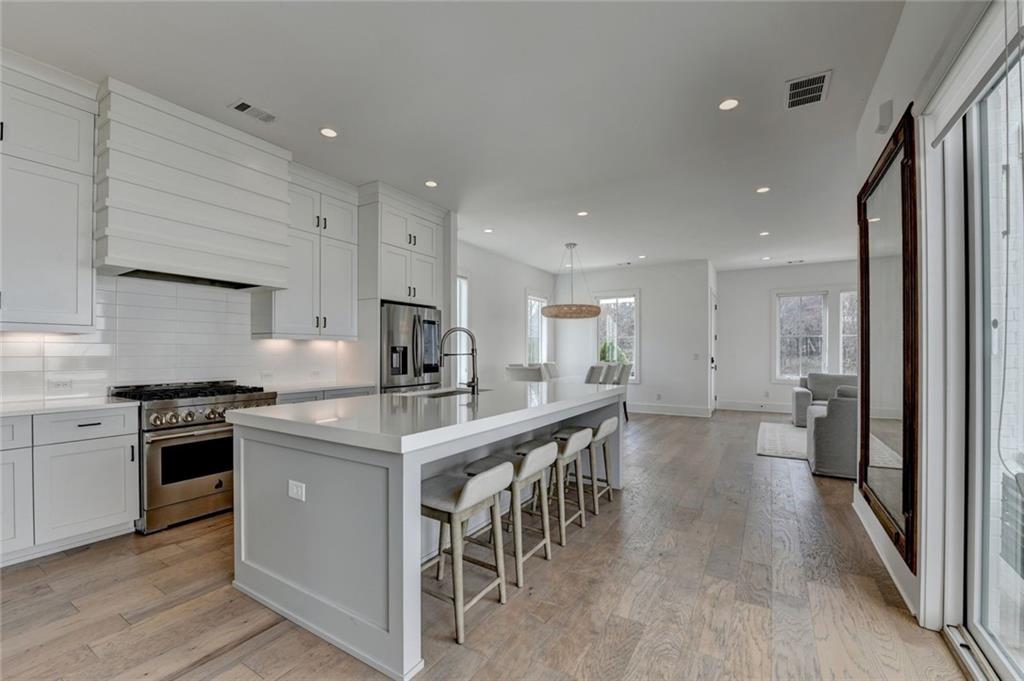 6785 Halcyon Way Alpharetta, GA 30005 - Photo 38 of 90 a kitchen with stainless steel appliances granite countertop a table chairs stove a sink dishwasher and cabinets