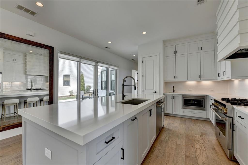 6785 Halcyon Way Alpharetta, GA 30005 - Photo 39 of 90 a large kitchen with stainless steel appliances granite countertop a stove top oven a sink a dining table and chairs