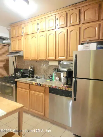 a kitchen with stainless steel appliances granite countertop a refrigerator a sink a stove and white cabinets