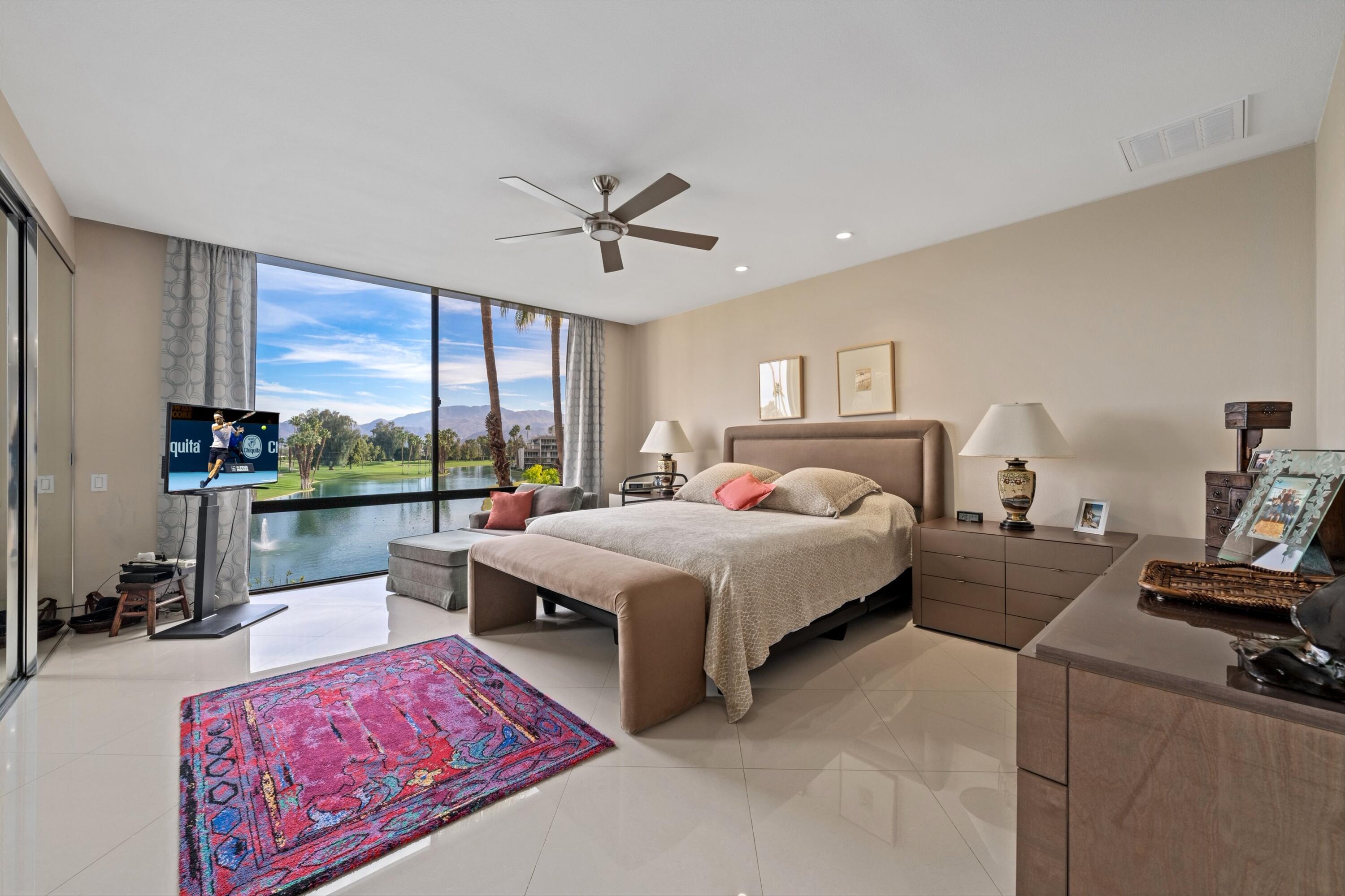 910 Island Drive, Unit 405 Rancho Mirage, CA 92270 - Photo 21 of 33 a spacious bedroom with a bed a large window with table and chairs