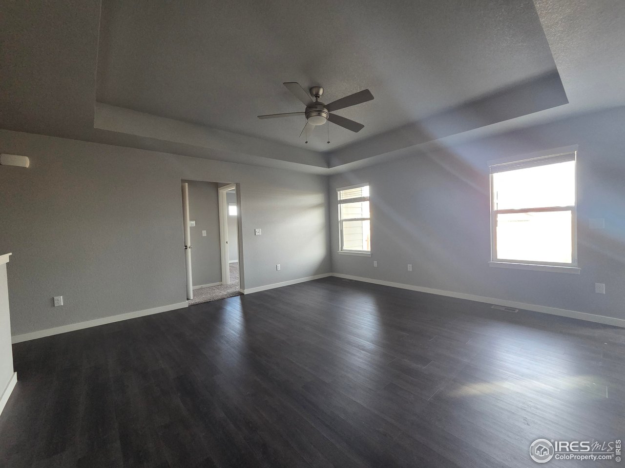 1203 Bison Way Wiggins, CO 80654 - Photo 2 of 17 an empty room with wooden floor and windows